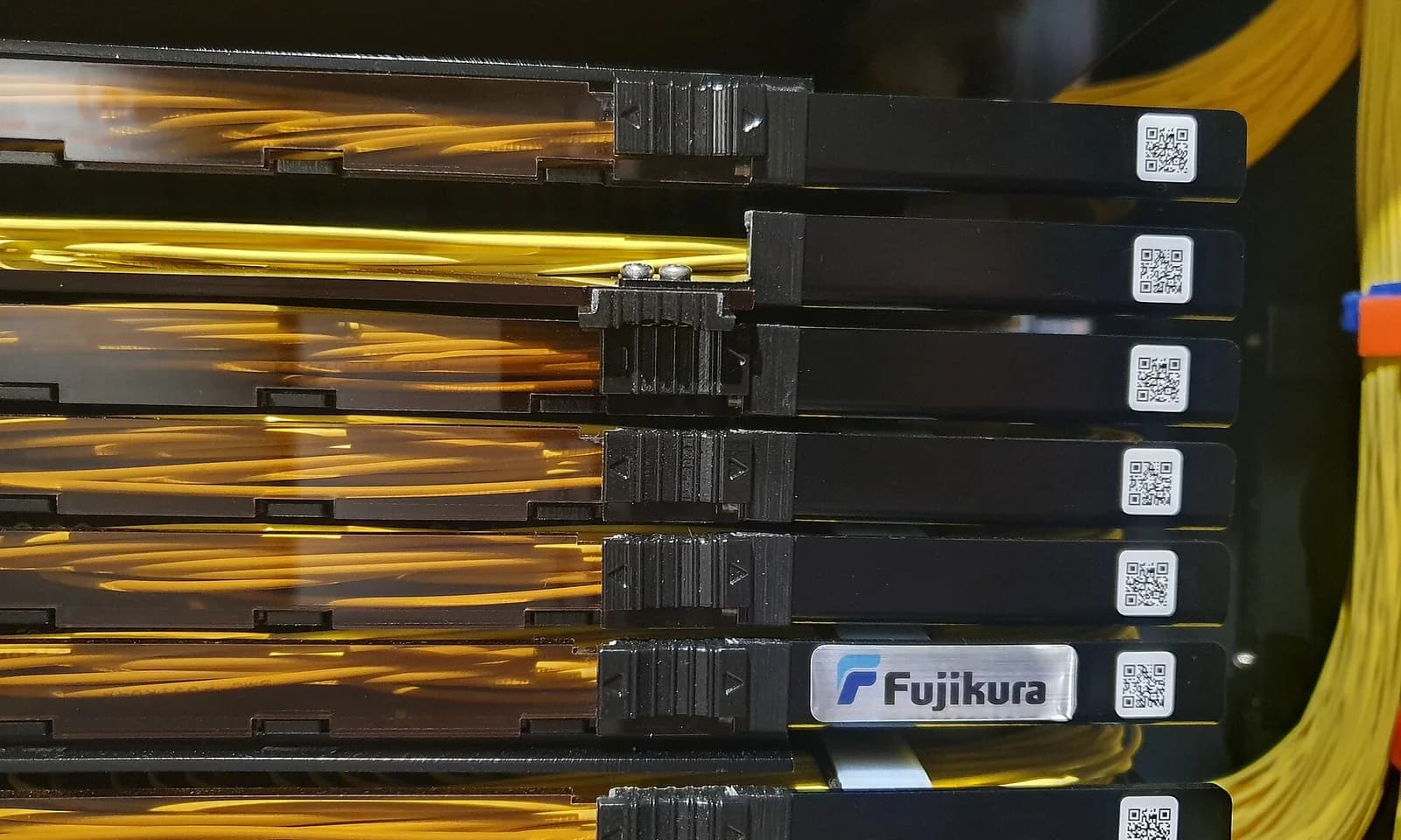 Fibre-optic cassettes in a rack, bundles of yellow fibre fanning out from each one