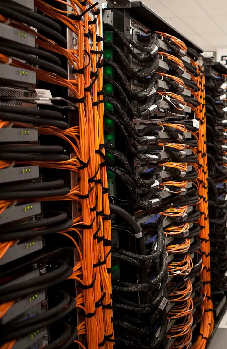 Supercomputer racks wrapped in bundles of orange cabling