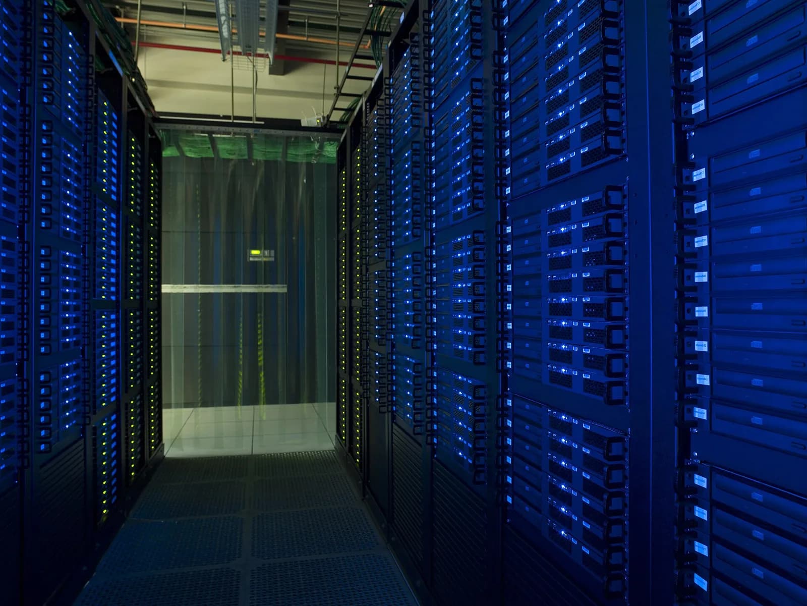 Aisle between server racks bathed in blue light at a grid computing centre